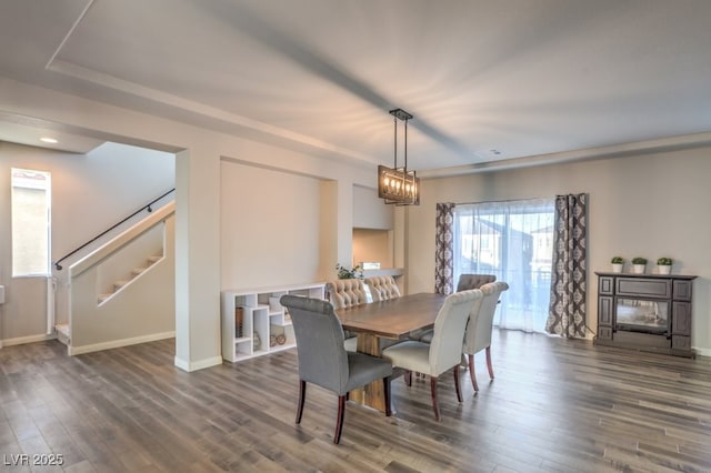 dining space featuring an inviting chandelier, stairway, wood finished floors, and baseboards