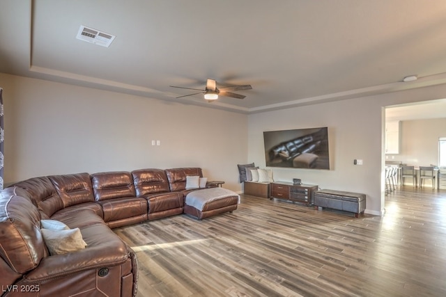 living area with visible vents, ceiling fan, and wood finished floors