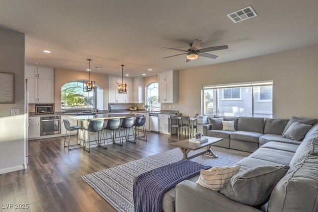 living room with dark wood-style floors, visible vents, recessed lighting, and ceiling fan