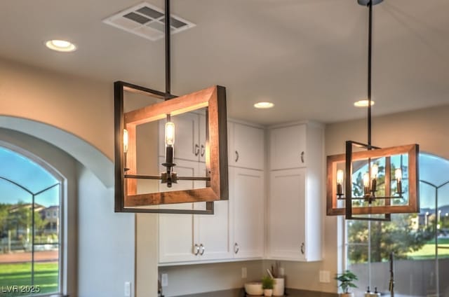 interior details featuring visible vents, dark countertops, recessed lighting, white cabinets, and hanging light fixtures