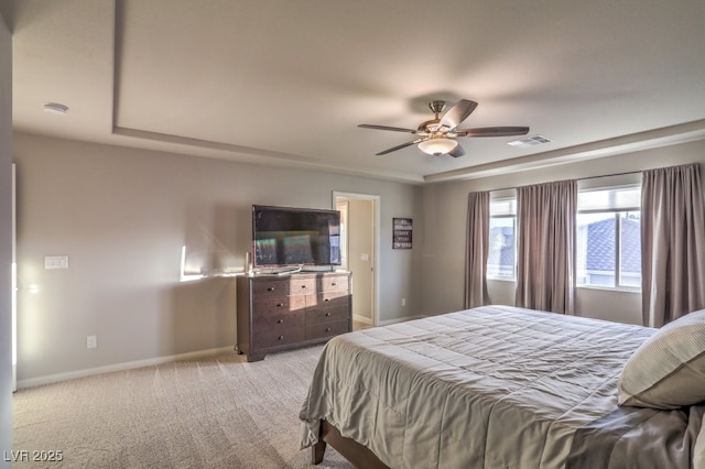 bedroom featuring baseboards, visible vents, a tray ceiling, ceiling fan, and light carpet