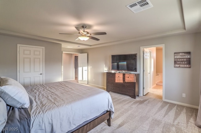 bedroom with baseboards, visible vents, ensuite bath, light carpet, and a raised ceiling