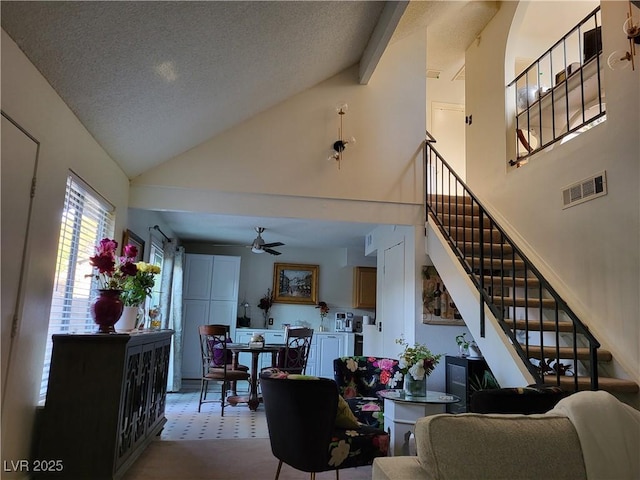 living room featuring ceiling fan, high vaulted ceiling, and a textured ceiling