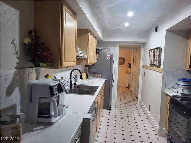 kitchen featuring dishwashing machine, sink, stainless steel refrigerator, tasteful backsplash, and light brown cabinetry