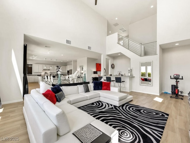 living room with a towering ceiling and light hardwood / wood-style floors