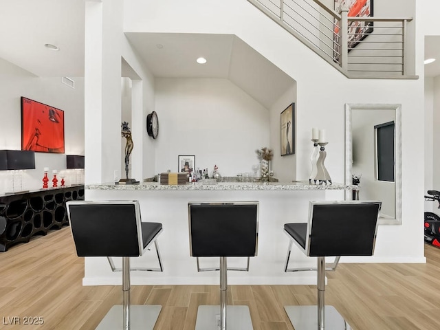 kitchen with hardwood / wood-style flooring, light stone countertops, and kitchen peninsula