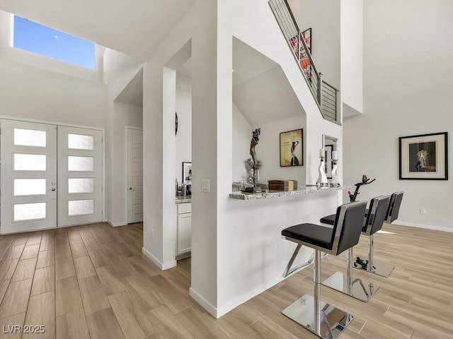 entryway featuring a high ceiling, light hardwood / wood-style floors, and french doors