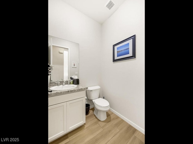 bathroom with hardwood / wood-style flooring, vanity, and toilet