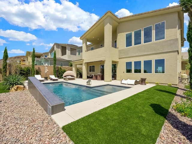 rear view of property featuring a fenced in pool and a patio area