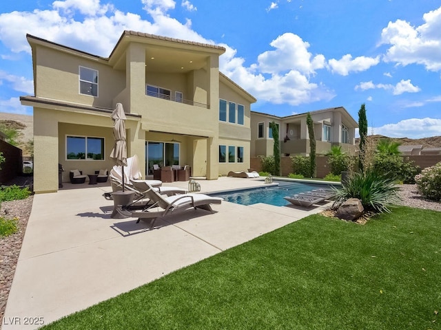 back of property featuring an outdoor living space, a fenced in pool, a patio, and a lawn