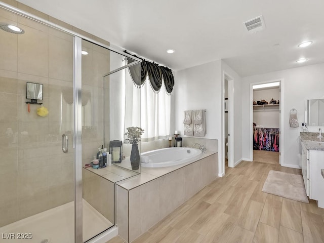 bathroom with plus walk in shower, hardwood / wood-style floors, and vanity