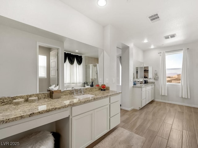 kitchen with sink, white cabinets, light stone counters, and light hardwood / wood-style flooring