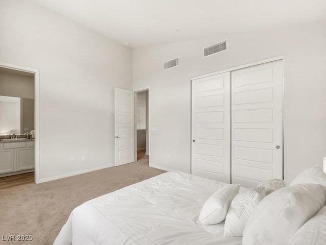 bedroom featuring vaulted ceiling, connected bathroom, sink, light colored carpet, and a closet