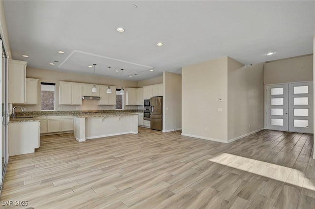 kitchen featuring pendant lighting, sink, a kitchen island, stainless steel fridge with ice dispenser, and light wood-type flooring