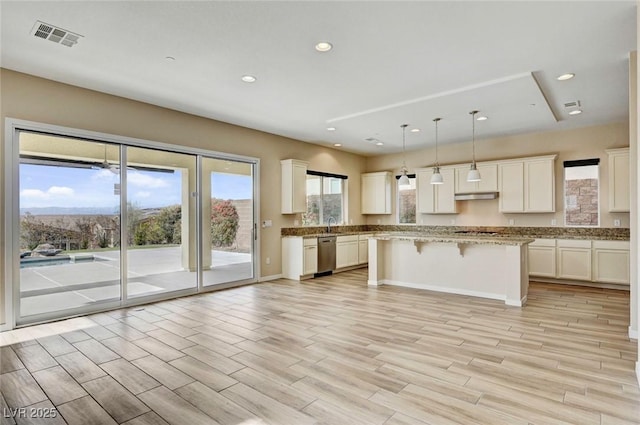 kitchen featuring white cabinetry, stainless steel dishwasher, decorative light fixtures, and a kitchen island