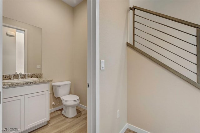 bathroom featuring wood-type flooring, vanity, and toilet