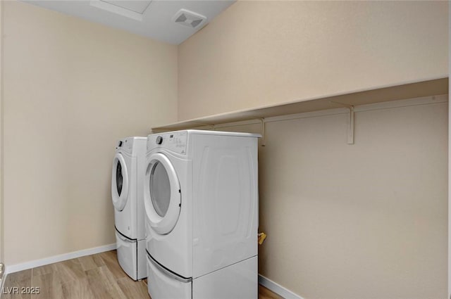 laundry room with washer and clothes dryer and light hardwood / wood-style flooring