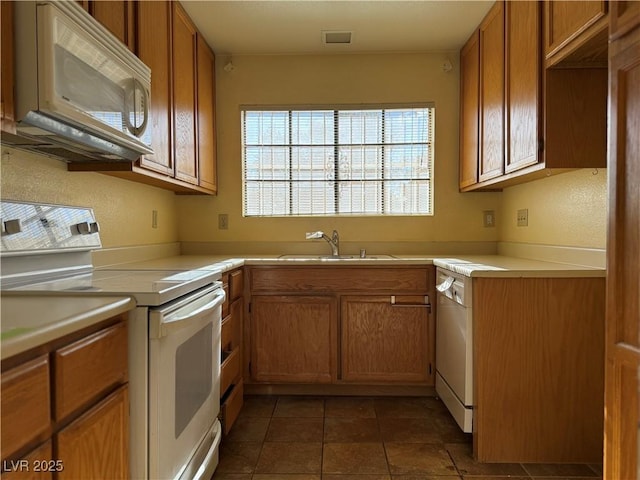 kitchen with white appliances, dark tile patterned flooring, and sink