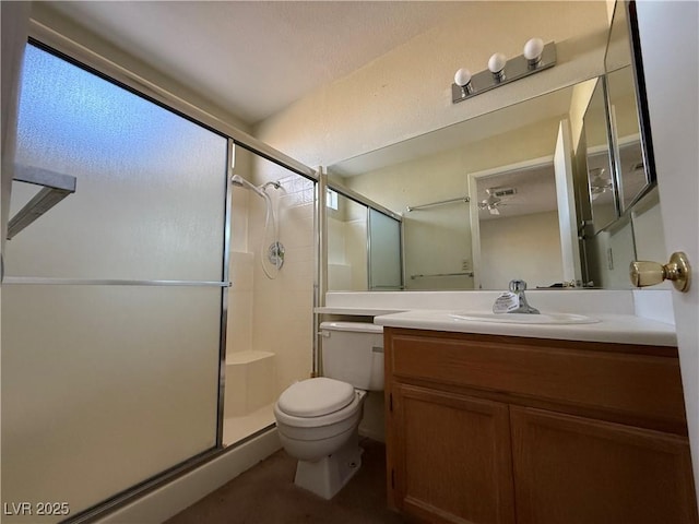 bathroom featuring a shower with door, vanity, and toilet