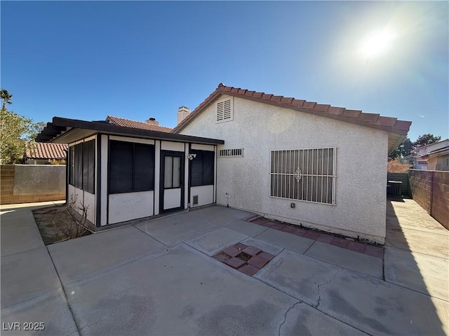 rear view of property with a sunroom, cooling unit, and a patio area