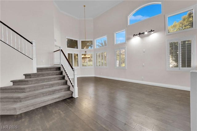 foyer entrance with a wealth of natural light, dark wood-type flooring, a chandelier, and a high ceiling