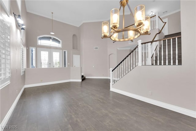 entryway with a towering ceiling, dark wood-type flooring, ornamental molding, and french doors