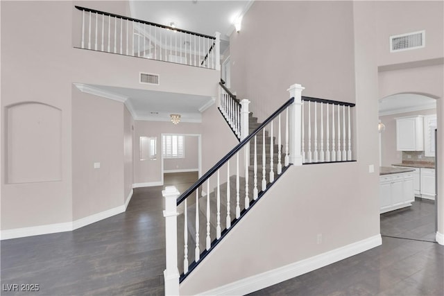 stairs with hardwood / wood-style floors, ornamental molding, and a high ceiling