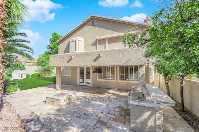 rear view of house with a fire pit, a patio, and an outdoor kitchen