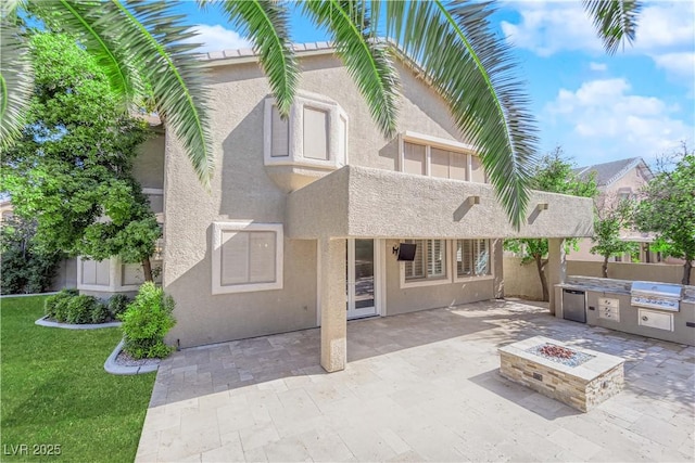 back of house featuring an outdoor fire pit, a yard, and a patio area