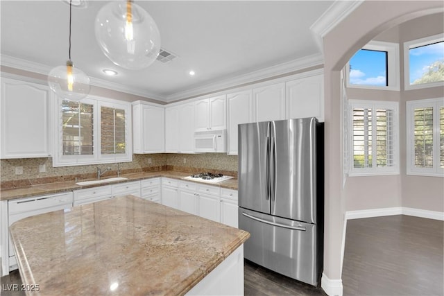 kitchen featuring sink, white appliances, white cabinetry, hanging light fixtures, and light stone counters