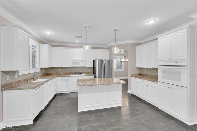 kitchen with stainless steel appliances, white cabinetry, a kitchen island, and pendant lighting