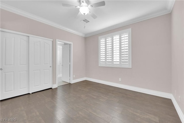 unfurnished bedroom with dark hardwood / wood-style flooring, crown molding, and a closet