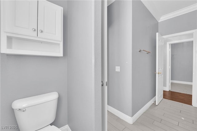 bathroom featuring wood-type flooring, ornamental molding, and toilet