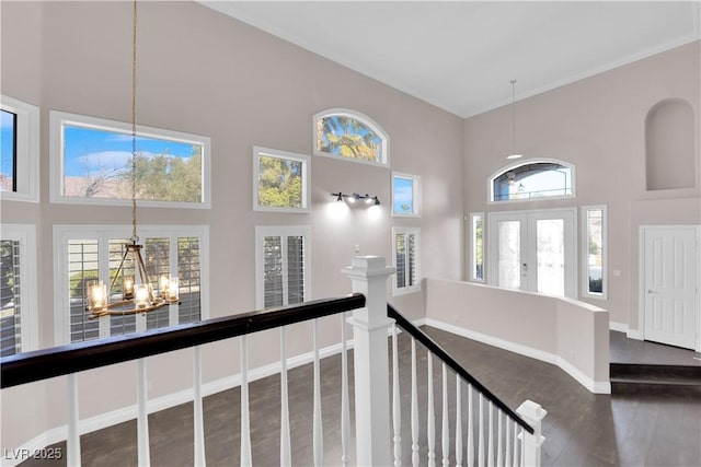 hall with french doors, a towering ceiling, dark hardwood / wood-style flooring, and a chandelier