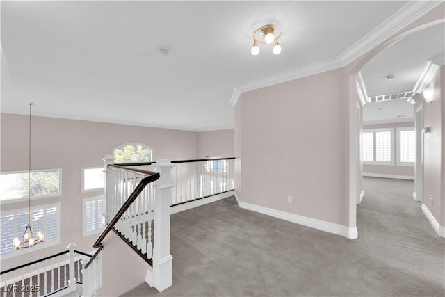 corridor featuring crown molding, light colored carpet, and a chandelier