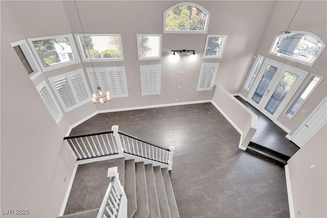 entryway featuring an inviting chandelier, a towering ceiling, and dark hardwood / wood-style floors