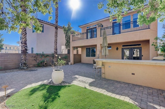 back of house with a patio, a balcony, a bar, and french doors