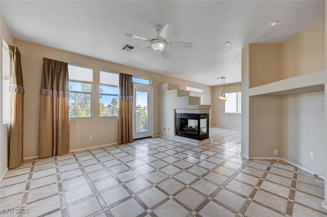 unfurnished living room featuring ceiling fan and a multi sided fireplace