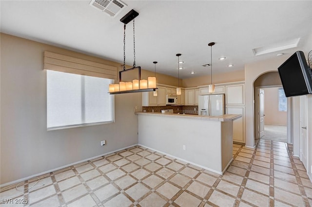 kitchen with pendant lighting, white appliances, and kitchen peninsula