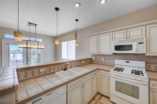 kitchen with pendant lighting, sink, tile counters, cream cabinets, and white appliances