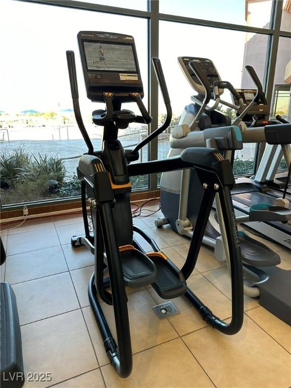 exercise room with light tile patterned flooring and a wall of windows