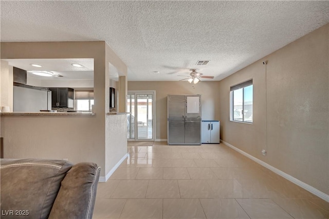 kitchen featuring fridge, light tile patterned floors, ceiling fan, kitchen peninsula, and a textured ceiling