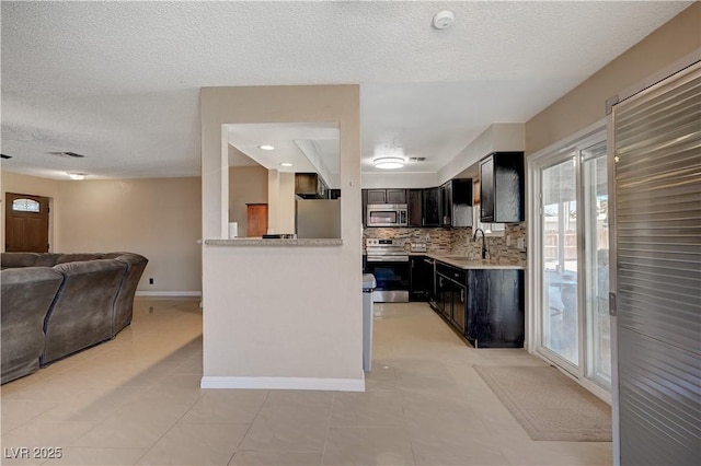 kitchen with appliances with stainless steel finishes, sink, backsplash, kitchen peninsula, and a textured ceiling