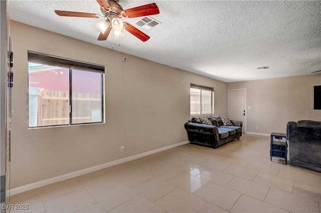 unfurnished living room with ceiling fan, a textured ceiling, and light tile patterned floors