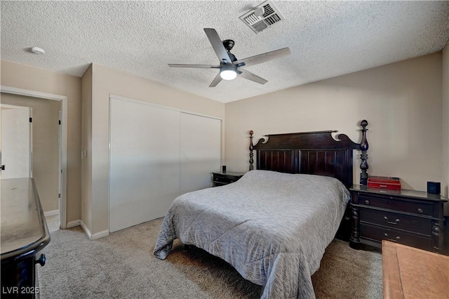 bedroom featuring ceiling fan, light colored carpet, a closet, and a textured ceiling