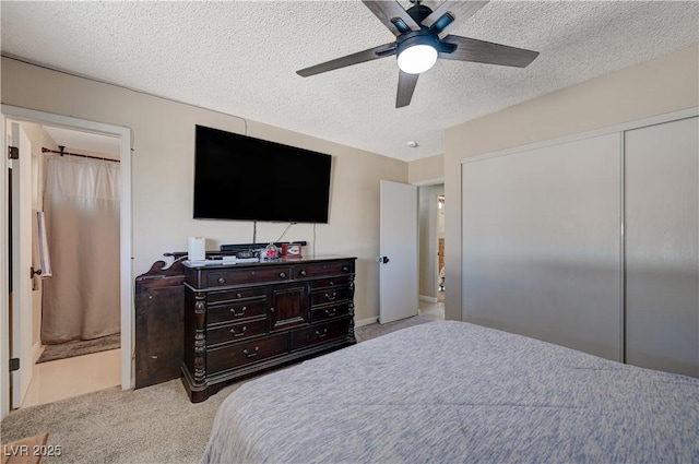 carpeted bedroom with ceiling fan, ensuite bath, a closet, and a textured ceiling