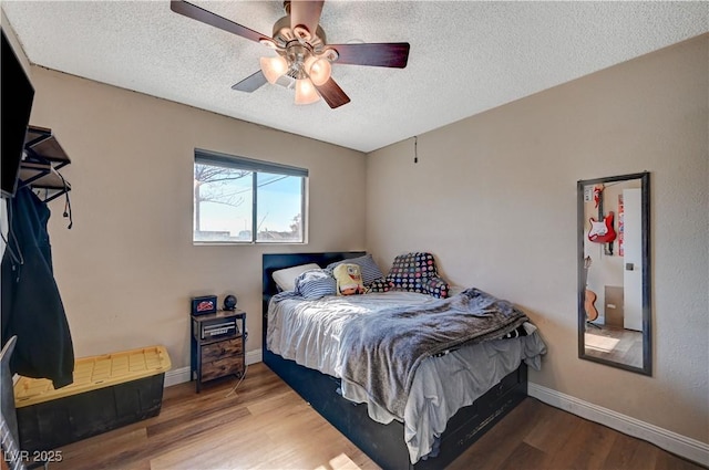 bedroom featuring ceiling fan, hardwood / wood-style floors, and a textured ceiling