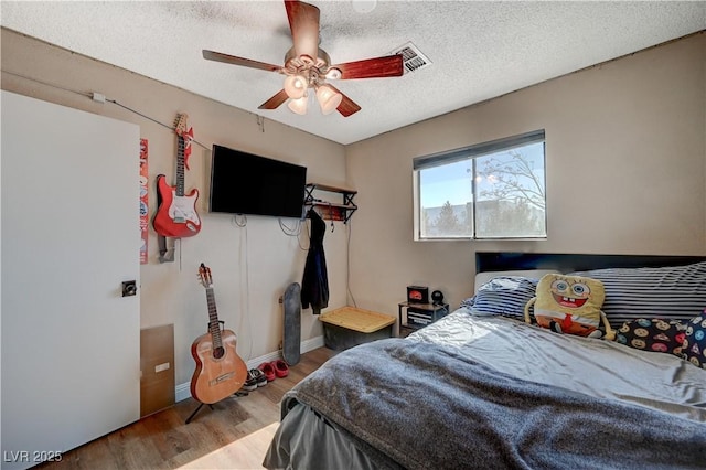 bedroom with ceiling fan, a textured ceiling, and light wood-type flooring