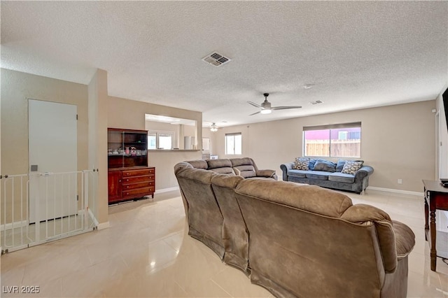 living room featuring light tile patterned floors, a textured ceiling, and ceiling fan