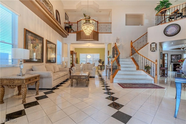 entrance foyer with a towering ceiling, light tile patterned flooring, a chandelier, and ornate columns